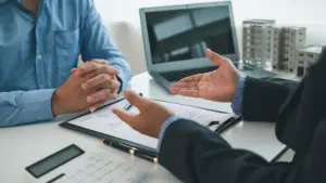 A government agency HR executive sitting at a desk, facing an employee discussing an internal equity complaint.